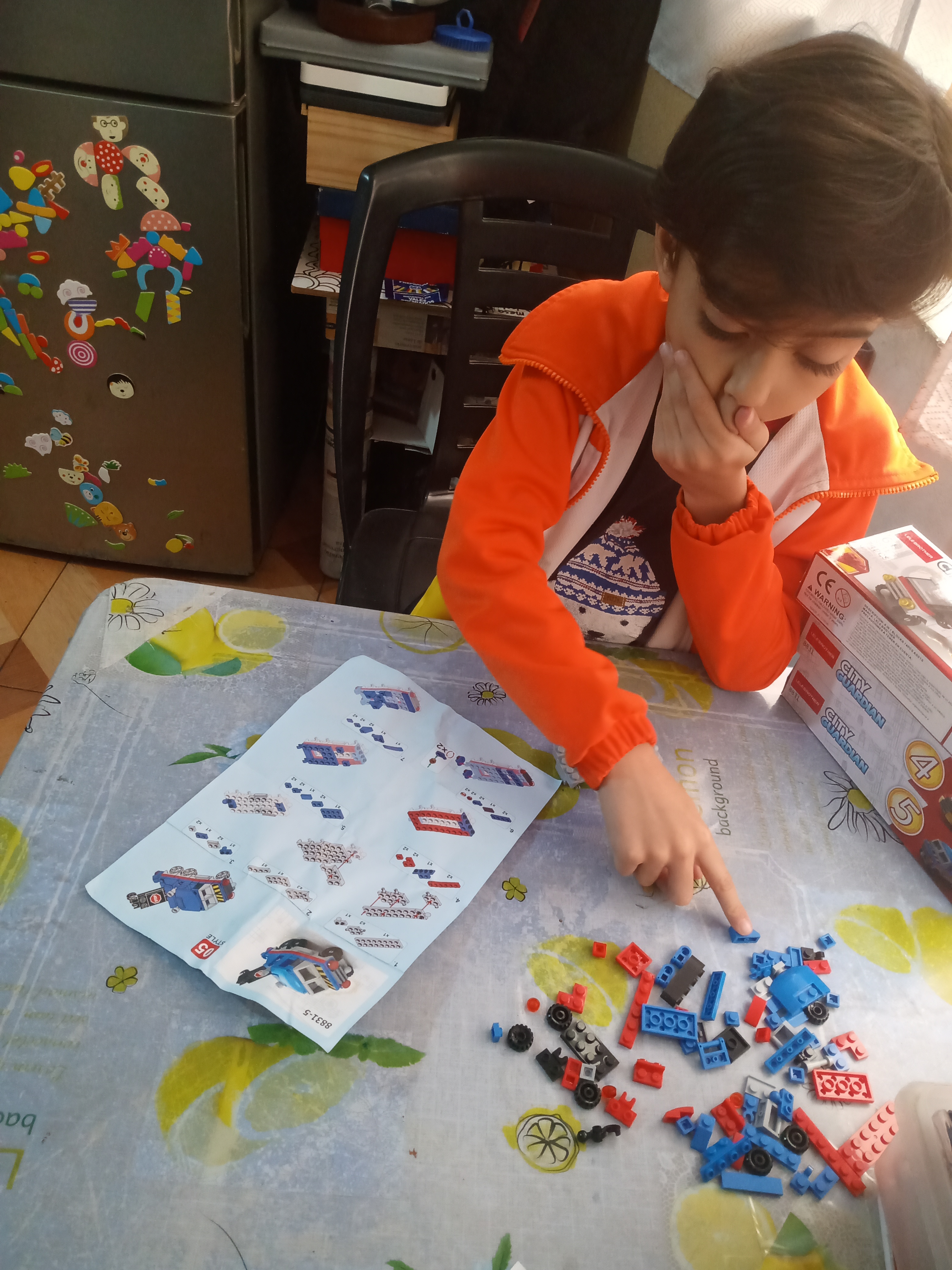 Niño concentrado leyendo instrucciones ilustradas para armar robot con bloques