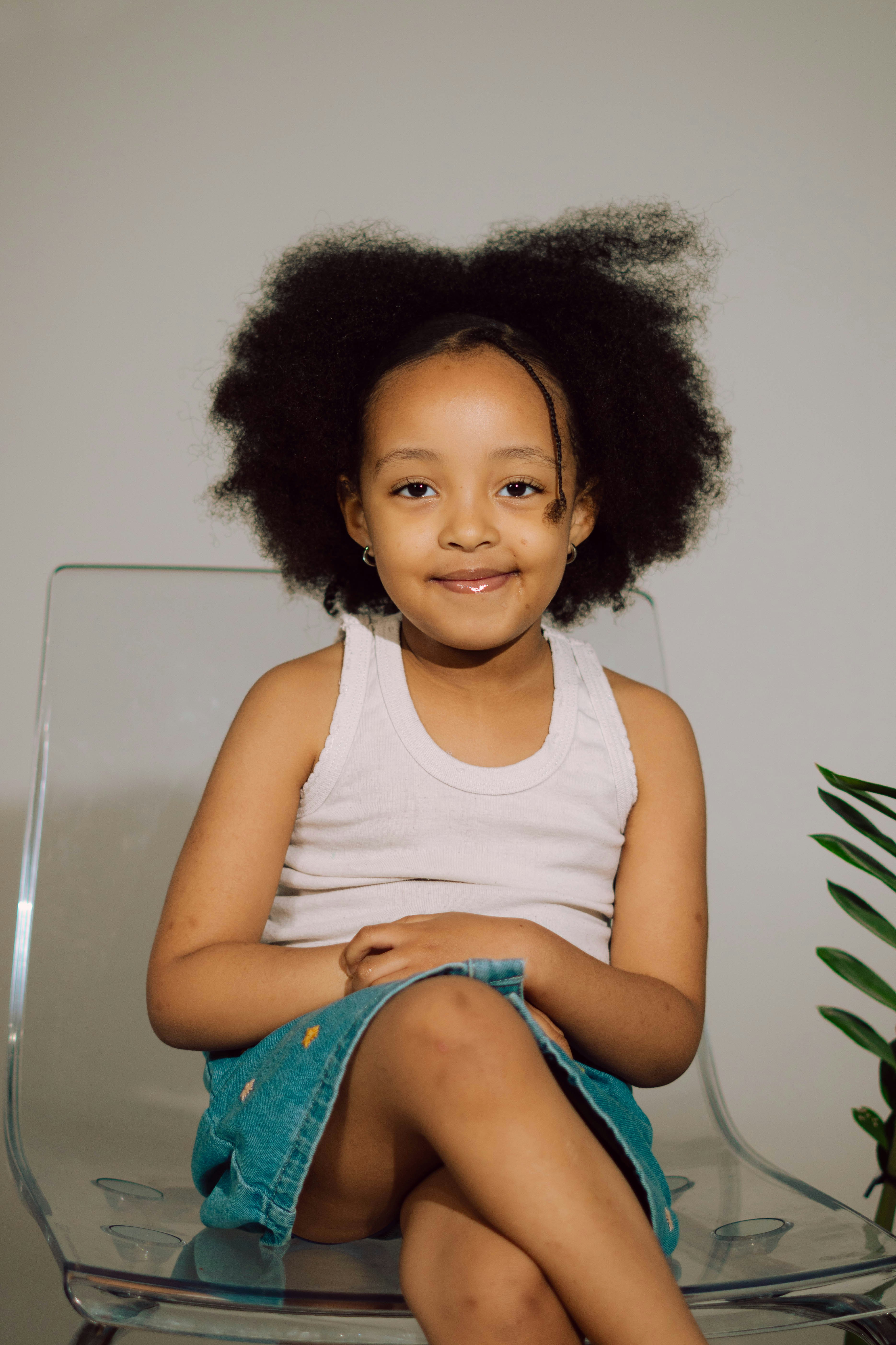 iña sonriente de cabello afro, sentada y mirando a la cámara con confianza