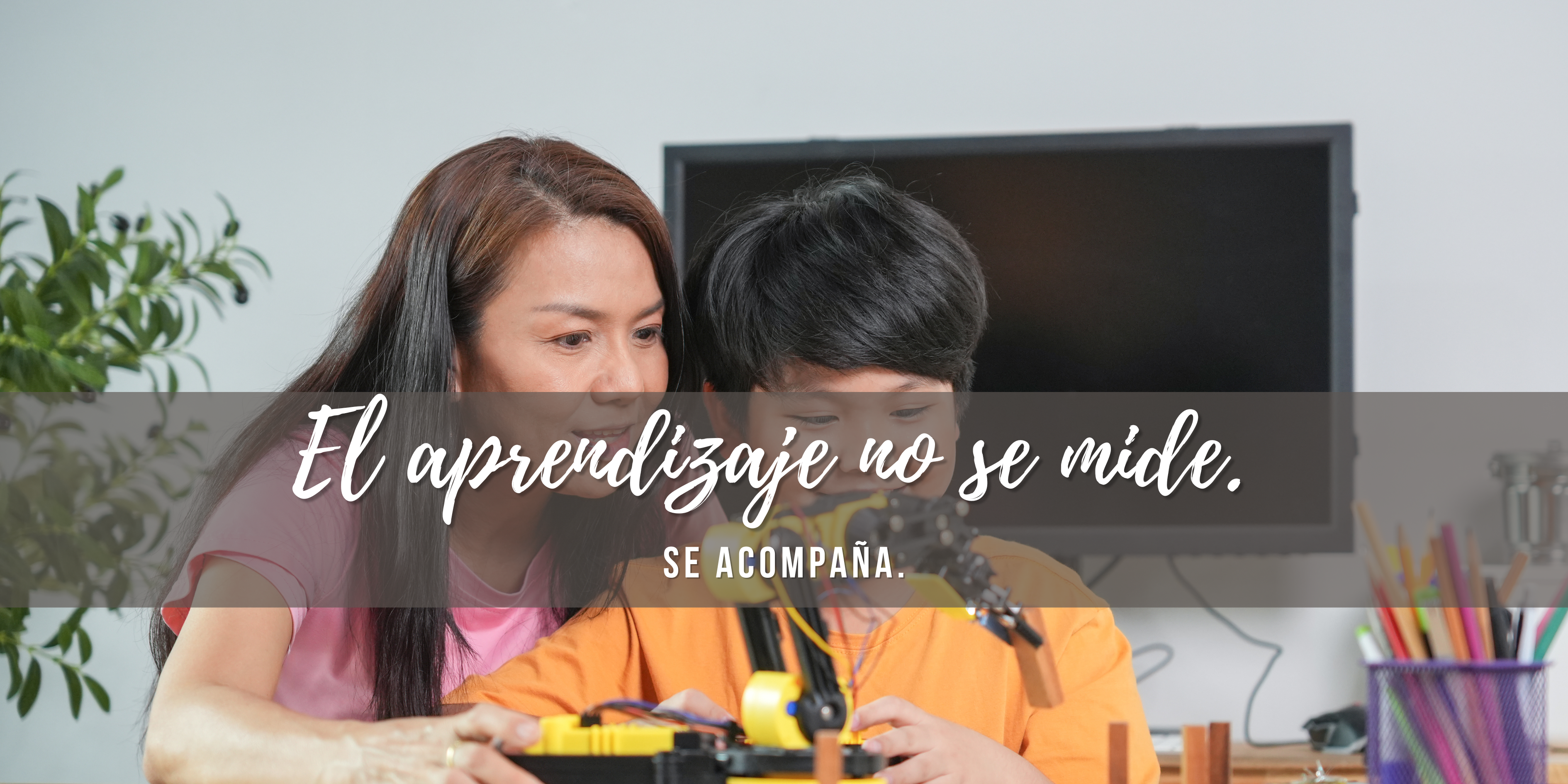 Niño construyendo un robot con brazo mecánico junto a su madre, ejemplo de aprendizaje sin escuela