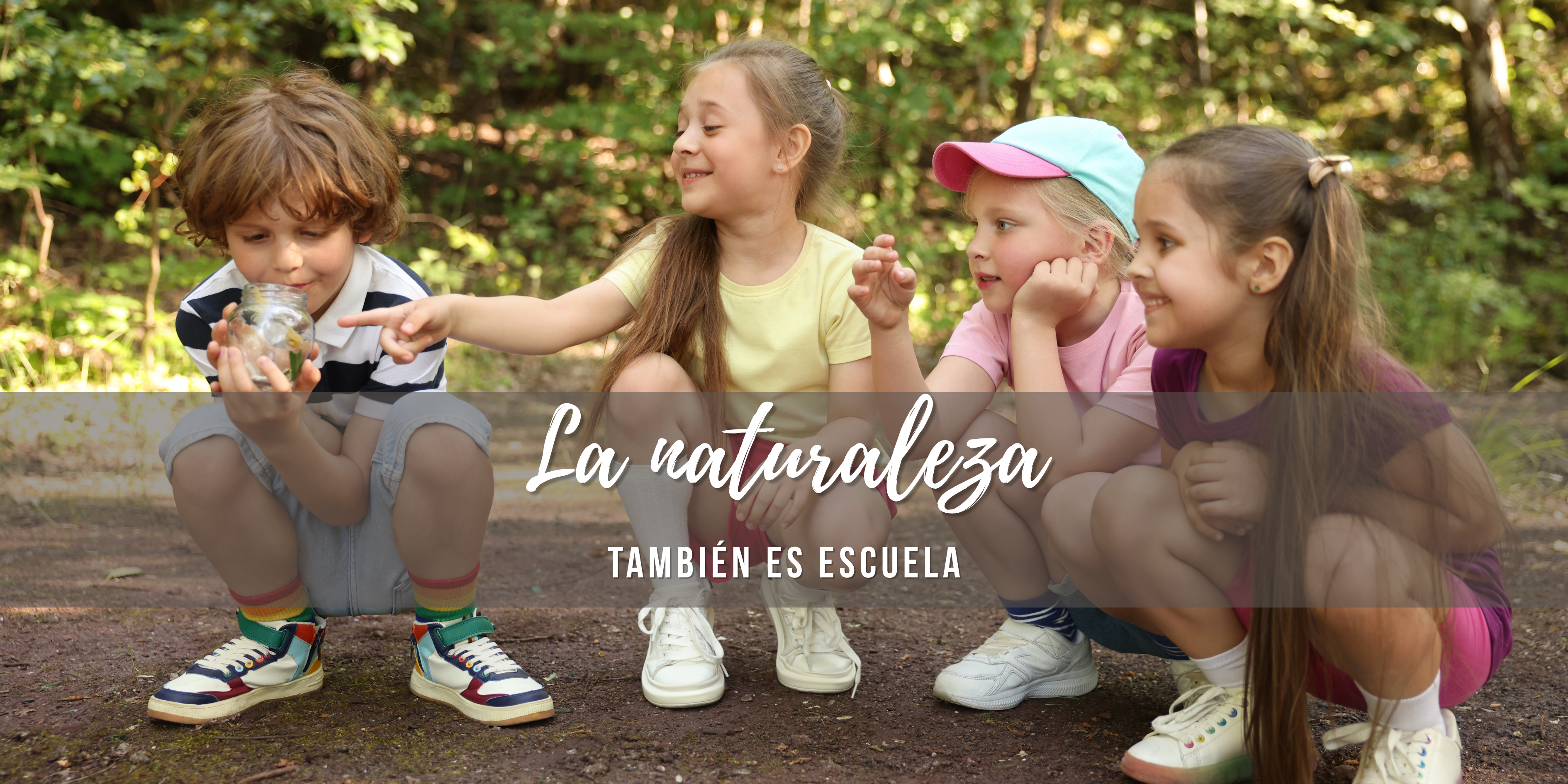 Cuatro niños agachados observan atentamente un pequeño insecto dentro de un frasco, en un claro de tierra rodeado de naturaleza.