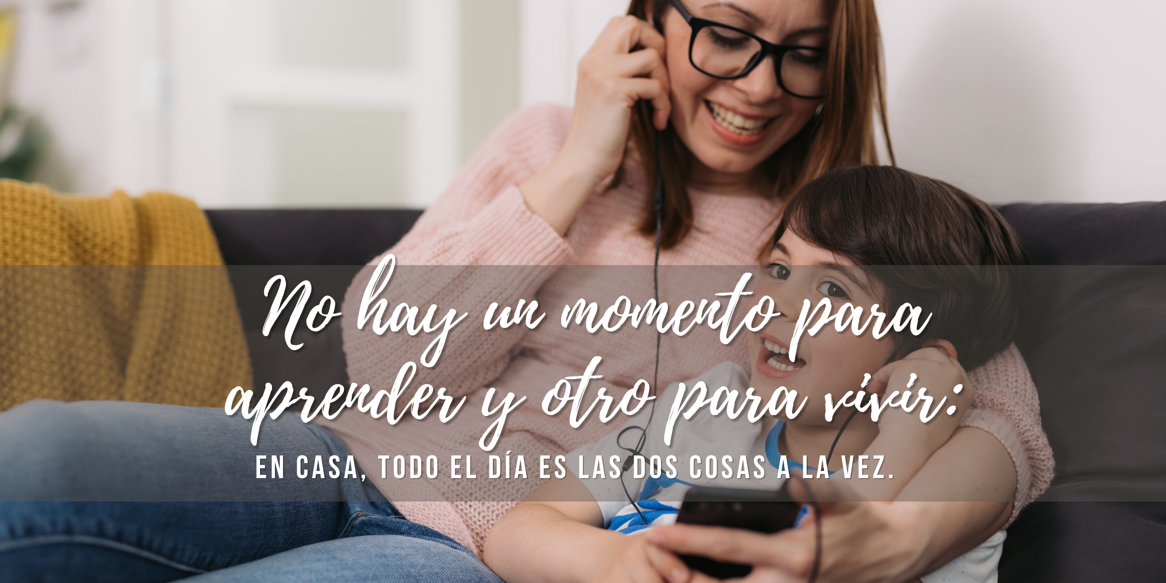 Madre e hijo sentados en el sofá compartiendo audífonos mientras escuchan algo juntos, ilustrando la frase 'No hay un momento para aprender y otro para vivir: en casa, todo el día es las dos cosas a la vez.