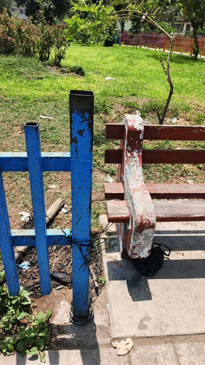 Una vieja banca de madera en un parque descuidado y sucio. 