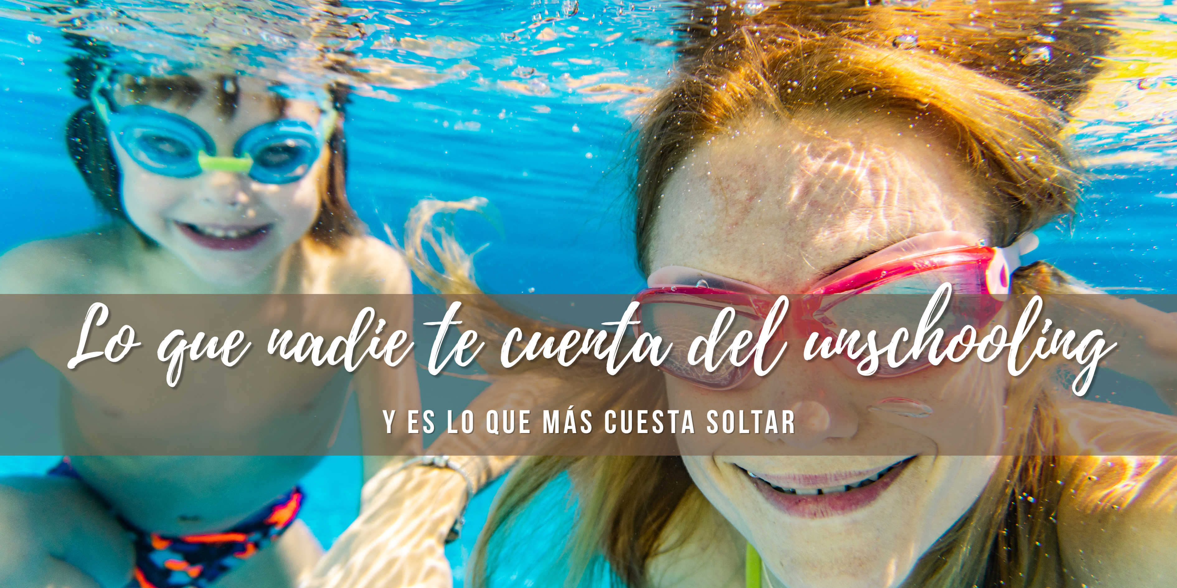Madre e hijo sumergidos en la piscina, mientras ella lo sostiene de la mano. 